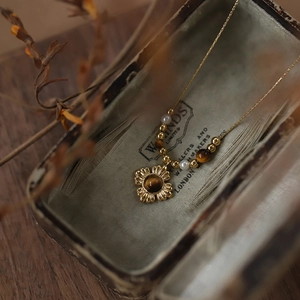 Detailed macro of vintage sunflower pendant with tiger eye stone and pearls on gold chain