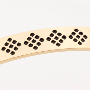 Golden C-shaped stainless steel cuff bracelet with black geometric grid pattern details