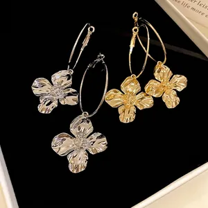Eleganti orecchini a cerchio in metallo oro e argento con petali testurizzati su velluto