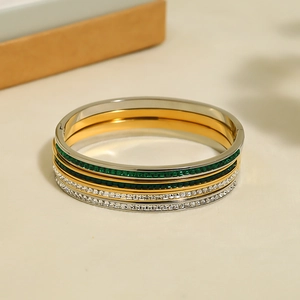 Detail of stacked gold and silver plated stainless steel bangles with colorful gemstones
