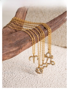Detail of gold zodiac necklaces with sparkling crystals hanging on a wooden stand