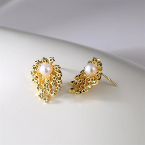 Détail des boucles d'oreilles étoiles dorées avec pierres vertes et perles blanches