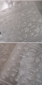 Detail von 3D-Präge-Nagelaufklebern mit weißen Lilien, Schmetterlingen und Liebesmotiven