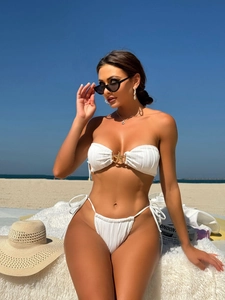 Detail of white ribbed bikini top featuring a golden starfish charm and tie-side bottoms