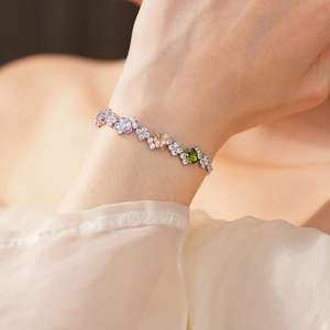 Close-up of a silver geometric bracelet with multi-colored oval zircon stones on wrist