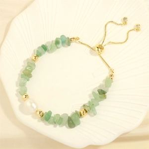 Detail of handmade elastic bracelet with green gemstones, white pearl and gold slider