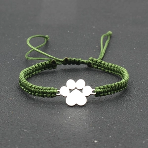 Detail of hand-woven green nylon rope bracelet with silver metal paw print charm