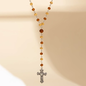 Detail of vintage gothic rosary necklace with amber faceted beads and ornate silver cross