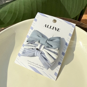 Three striped bow hair clips set in blue and white fabric displayed on a white tray