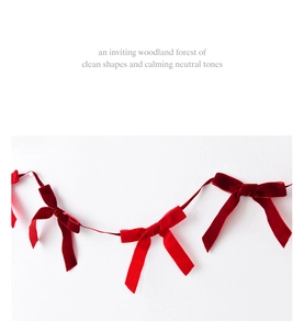 Detail of premium red velvet bow garland hanging against a clean minimalist white wall
