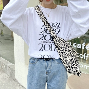 Close-up of leopard print canvas crossbody bag paired with a white long-sleeve T-shirt