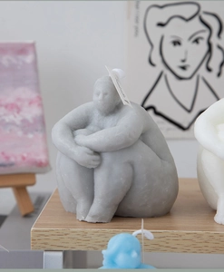 Artistic close-up of handmade torso candles in grey, white, and blue for home decor