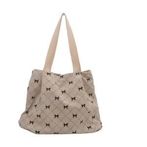 Beige corduroy quilted tote bag with black bow patterns and dual woven handles