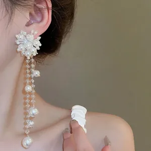 Elegant floral pearl cluster earrings with long beaded tassels on model view