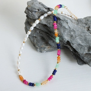 Handmade Baroque pearl and colorful natural stone necklace on grey rock background