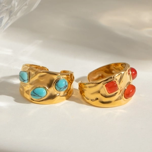 Macro detail of gold-plated hammered rings featuring turquoise and vermilion gemstones