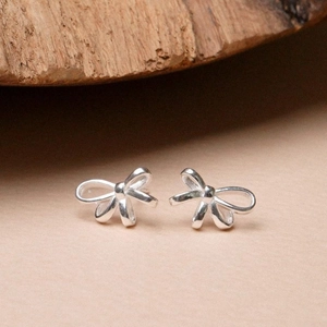 Elegant 925 sterling silver bow knot stud earrings displayed on a natural wooden surface