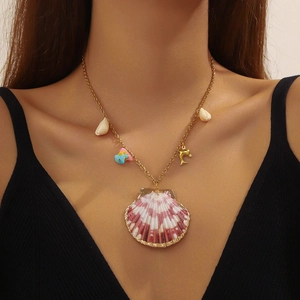 Detail of gold necklace featuring shell, starfish, and dolphin charms for vacation style
