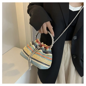 Detail of colorful striped straw bucket bag with silver metal ring handle and chain strap