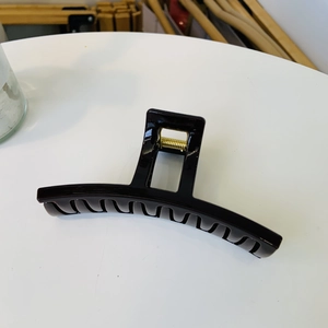Macro shot of large black glossy shark hair clip with durable golden metal spring