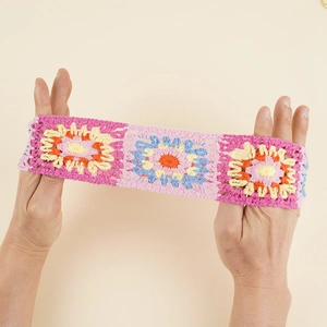 Detail showing the high elasticity of a hand-knitted floral headband with crochet patterns