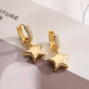 Macro detail of gold-plated star drop earrings featuring crystal pavé hoops and polished finish