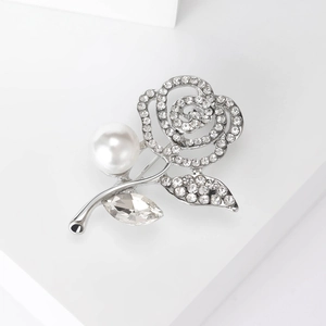 Detailed view of silver rose brooch with sparkling rhinestones and a white pearl accent