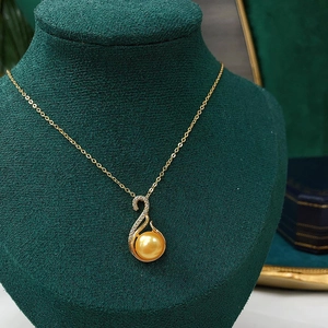 Macro shot of gold swan pendant with freshwater gold pearl on a green velvet stand