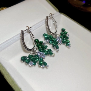 Vue macro de boucles d'oreilles papillon avec cristaux verts dans un coffret blanc