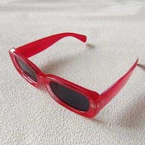 Detail of red rectangle frame sunglasses with dark lenses and retro Y2K fashion style