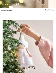Detail showing a white plush Christmas angel ornament being hung on a tree branch