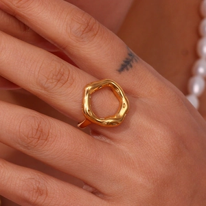Close-up of gold-plated stainless steel hollow ring with organic irregular design