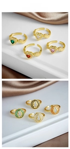 Detail of gold-plated open rings featuring Hamsa hand and heart designs with colorful zircons
