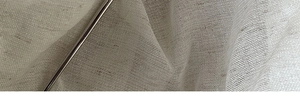 Macro shot of light-colored woven linen fabric texture with a metallic hair stick detail