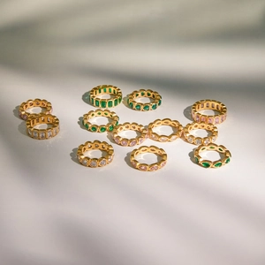 Detailed set of eleven gold-tone rings featuring emerald green and pink zirconia stones