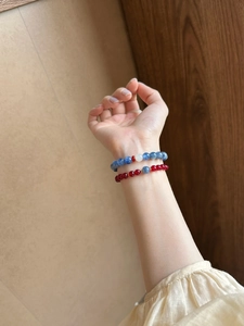 Detail of blue kyanite and red agate beaded bracelets on woman wrist in natural light