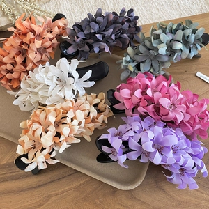 Elegant floral hair claw clips in various colors displayed on a wooden tray