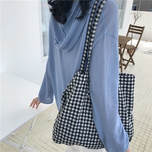 Side view of a large black and white checkered canvas tote bag worn by a model