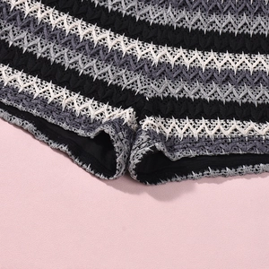 Detailed close-up of textured black and white wave pattern knit fabric and stitching