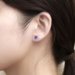 Minimalist square blue zircon stud earring with claw setting shown on a model's ear