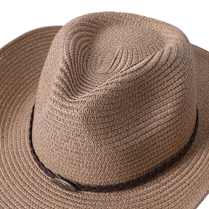Détail d'un chapeau de cowboy tissé avec bande en cuir marron et emblème rhino en métal