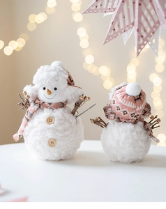 Close-up of plush pink snowman ornaments with knit hats and rustic wooden buttons