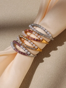 Detail of luxury pearl and zircon rings on champagne satin with gold and silver finishes