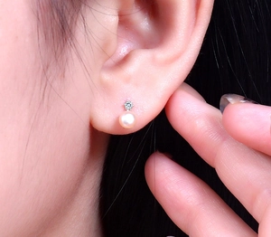 Close-up of pink-white freshwater pearl stud earrings with crystal on model's ear