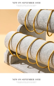 Close-up of golden bangle bracelets on ice grey velvet T-bar display stand stand