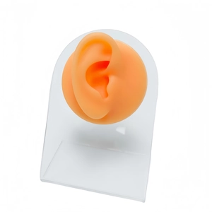Orange silicone ear model for piercing practice displayed on a clear acrylic stand