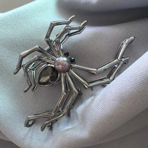 Detail shot of silver spider hair claw with purple pearl and teardrop gemstone on blue fabric