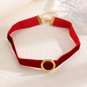 Dettaglio choker in velluto rosso con chiusura a cerchio dorata e catena regolabile