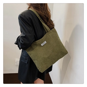 Close-up of olive green corduroy tote bag featuring a Fashion label and textured surface