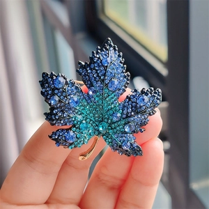 Close-up of luxury maple leaf brooch with blue gradient crystals on gold alloy